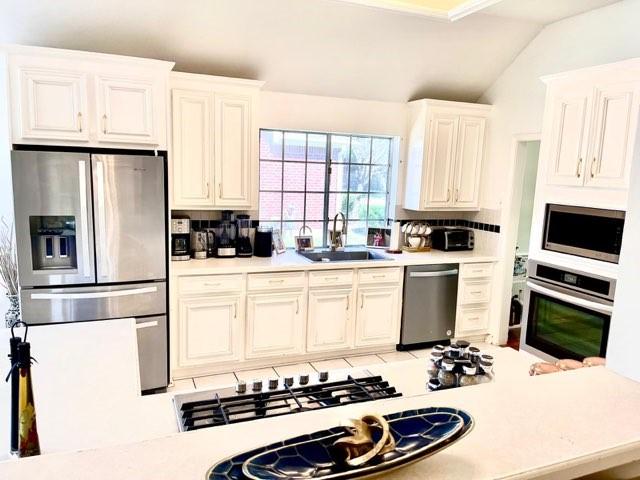 23006 Greenrush Dr, Katy, TX 77494 - kitchen featuring tasteful backsplash, a sink, light countertops, stainless steel appliances, and lofted ceiling