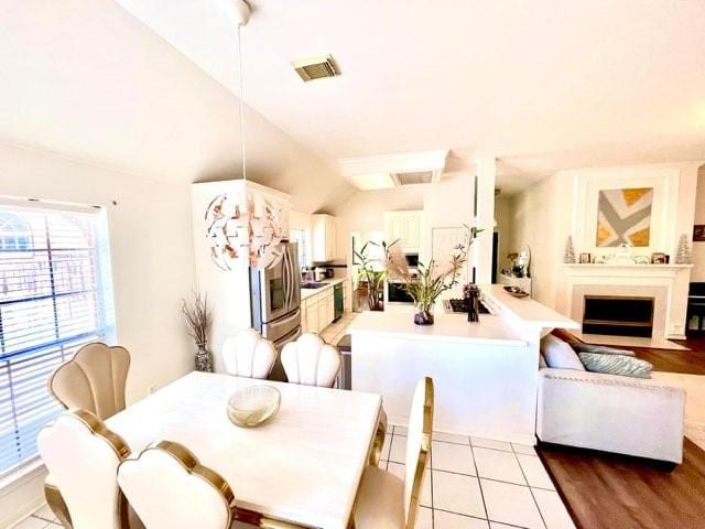 23006 Greenrush Dr, Katy, TX 77494 - dining area with a fireplace with flush hearth, light tile patterned floors, visible vents, and lofted ceiling