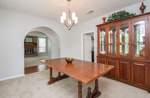 dining area with arched walkways, a textured ceiling, visible vents, a chandelier, and light carpet