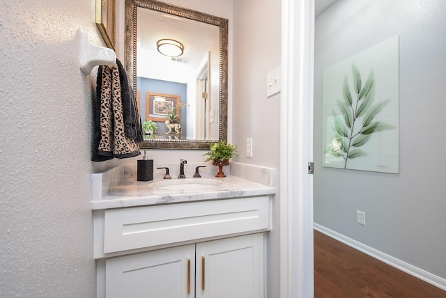 bathroom featuring vanity, baseboards, visible vents, and wood finished floors