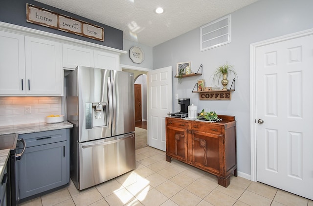 kitchen featuring tasteful backsplash, light tile patterned floors, arched walkways, stainless steel refrigerator with ice dispenser, and white cabinetry