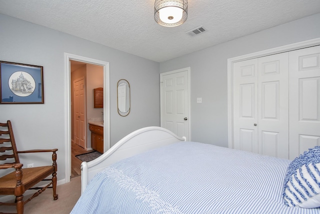 bedroom with visible vents, a closet, a textured ceiling, connected bathroom, and light carpet