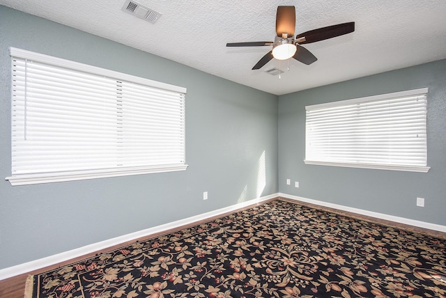 spare room featuring visible vents, baseboards, a textured ceiling, and ceiling fan