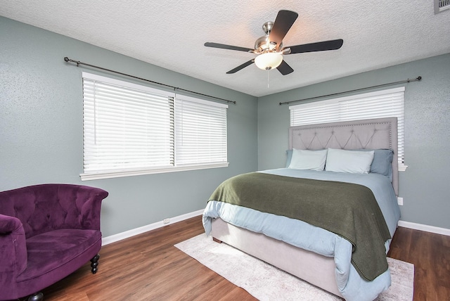 bedroom featuring baseboards, a ceiling fan, wood finished floors, and a textured ceiling
