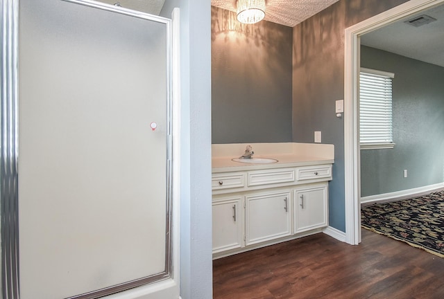 full bath featuring a stall shower, wood finished floors, vanity, and visible vents