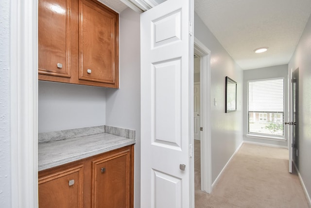hallway with light colored carpet and baseboards