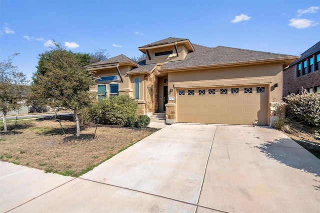 prairie-style house featuring a shingled roof, stone siding, a garage, concrete driveway, and stucco siding