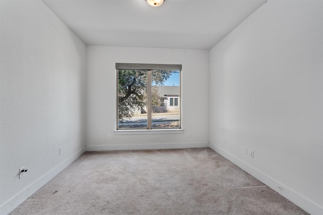 spare room featuring carpet floors and baseboards