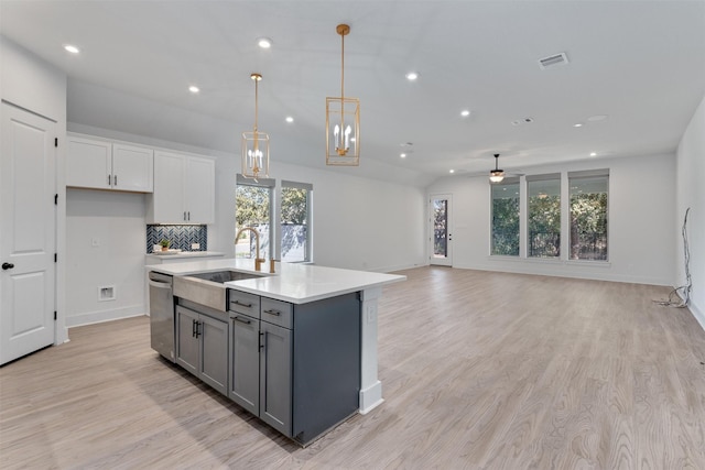 kitchen featuring ceiling fan, stainless steel dishwasher, gray cabinets, a sink, and light countertops