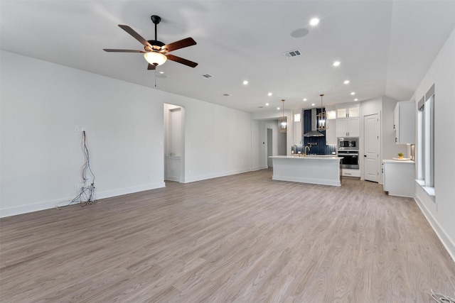 unfurnished living room featuring light wood-style flooring, a ceiling fan, visible vents, recessed lighting, and baseboards