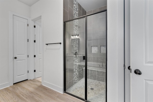 bathroom featuring baseboards, a shower stall, and wood finished floors