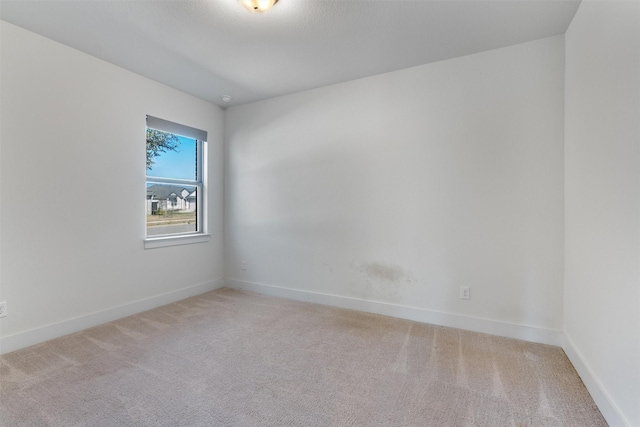 spare room featuring baseboards and light colored carpet