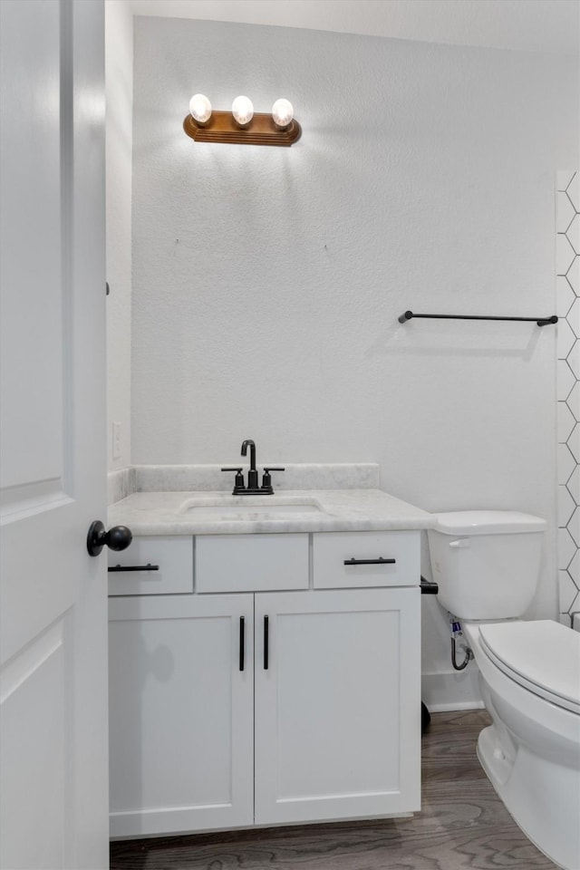 bathroom featuring toilet, vanity, and wood finished floors
