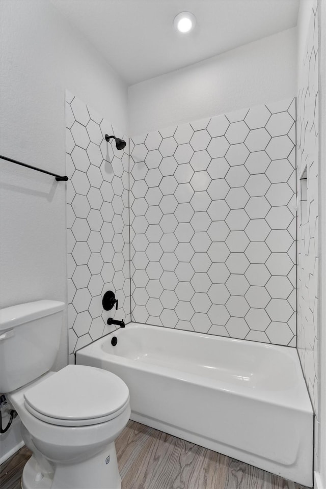 bathroom with shower / bathtub combination, toilet, and wood finished floors