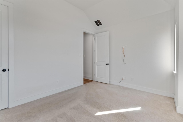 unfurnished room with visible vents, baseboards, lofted ceiling, and carpet floors
