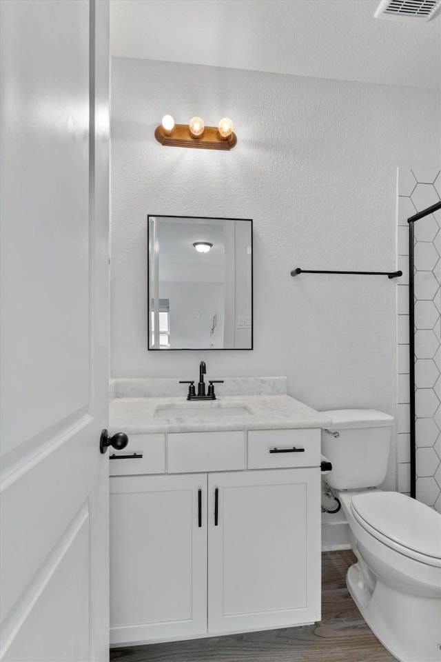 bathroom with visible vents, toilet, vanity, and wood finished floors