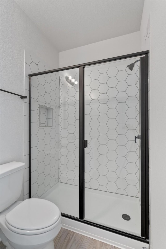bathroom featuring toilet and a shower stall