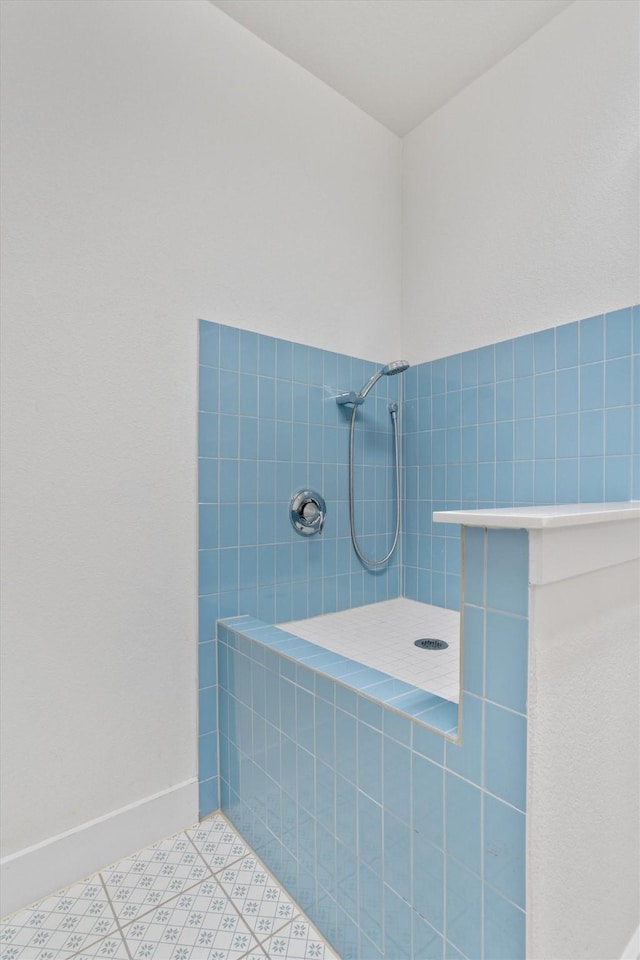 full bathroom featuring tile patterned flooring, baseboards, and a tile shower