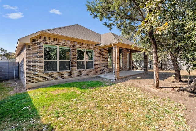 rear view of house with a patio area, brick siding, fence, and a lawn