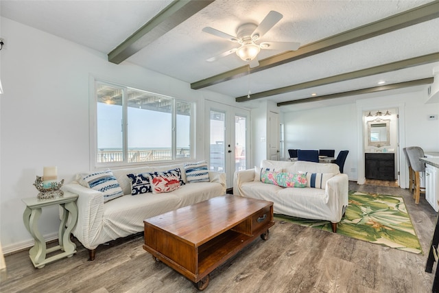 living room with baseboards, beamed ceiling, a ceiling fan, and wood finished floors