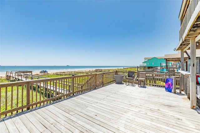 wooden terrace featuring a water view and a beach view