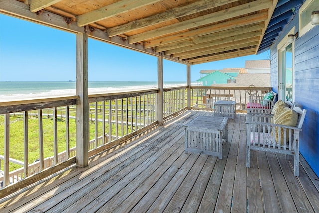 wooden deck featuring a water view and a view of the beach