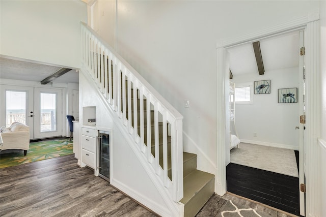 stairs with french doors, wood finished floors, baseboards, and beam ceiling