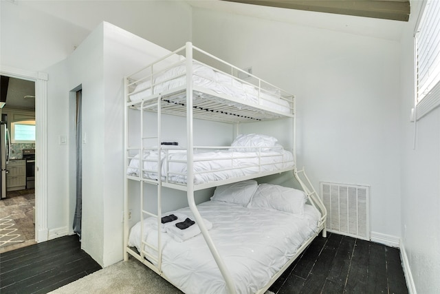 bedroom featuring hardwood / wood-style floors, freestanding refrigerator, baseboards, and visible vents