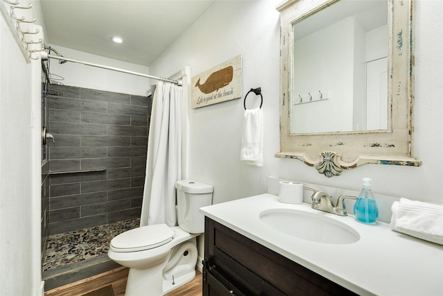bathroom featuring toilet, a stall shower, wood finished floors, and vanity