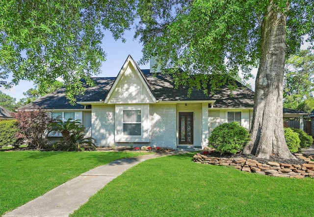 2327 Brookdale Dr, Kingwood, TX 77339 - tudor home with a front lawn, a shingled roof, and brick siding