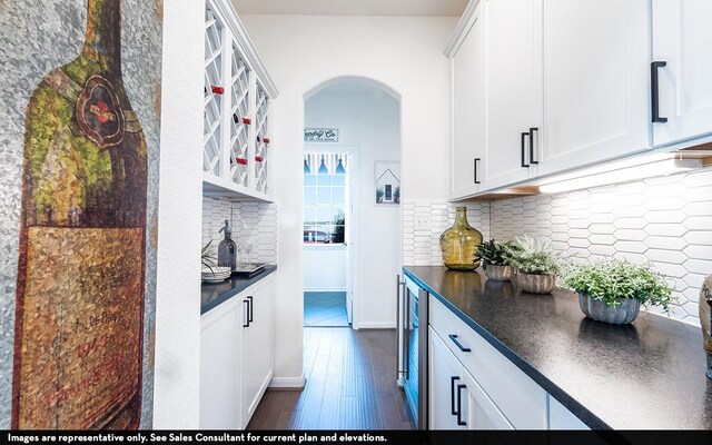 13724 Seneca Lake Dr, Texas City, TX 77568 - kitchen featuring white cabinets, arched walkways, dark countertops, dark wood-type flooring, and decorative backsplash
