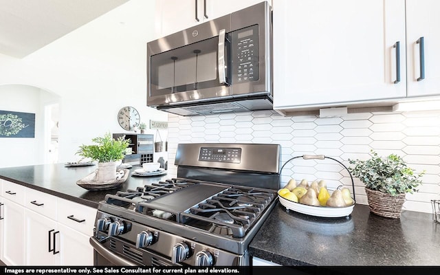 13724 Seneca Lake Dr, Texas City, TX 77568 - kitchen with white cabinets, arched walkways, dark countertops, appliances with stainless steel finishes, and decorative backsplash