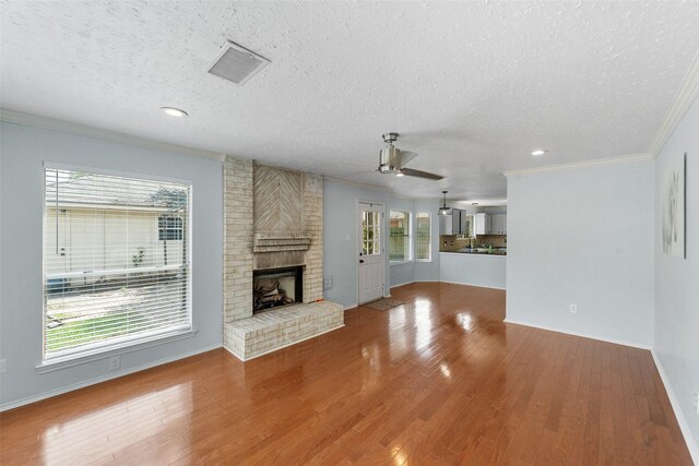 unfurnished living room with a ceiling fan, visible vents, a textured ceiling, and crown molding