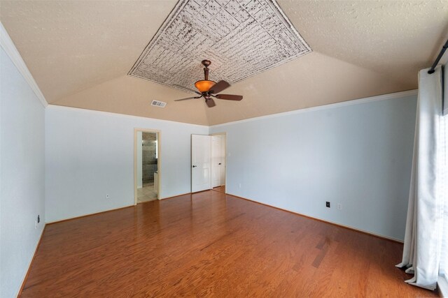 unfurnished bedroom featuring vaulted ceiling, ornamental molding, wood finished floors, and visible vents