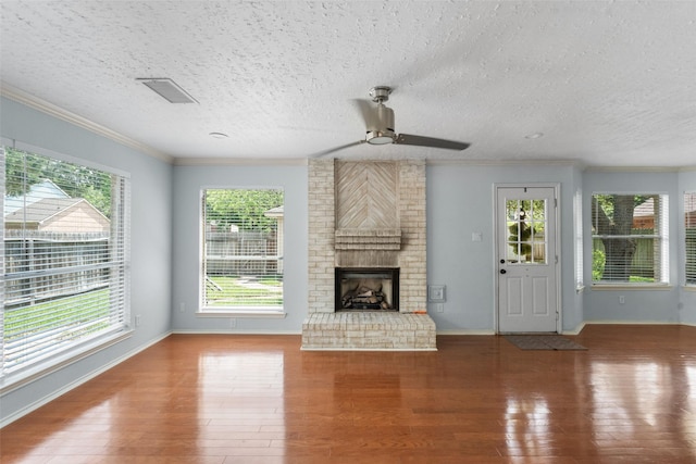 unfurnished living room with ceiling fan, crown molding, a brick fireplace, and wood finished floors
