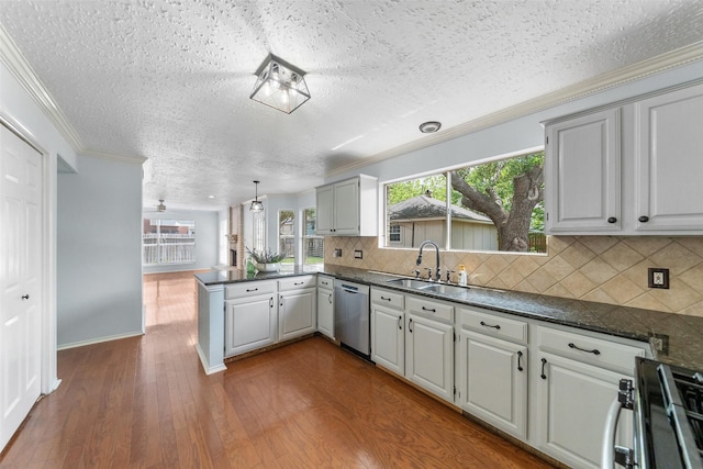 kitchen with a sink, a textured ceiling, a peninsula, appliances with stainless steel finishes, and dark wood-type flooring