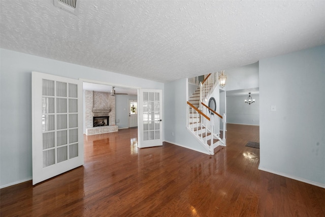 unfurnished living room featuring stairway, wood finished floors, visible vents, french doors, and a textured ceiling