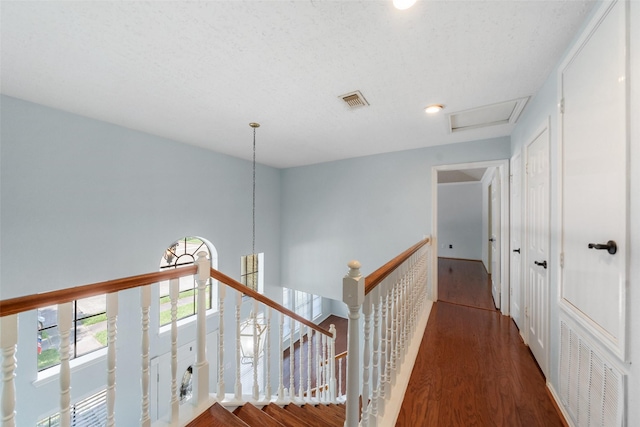 corridor featuring attic access, wood finished floors, visible vents, and an upstairs landing
