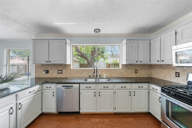 kitchen featuring stainless steel appliances, a sink, crown molding, a textured ceiling, and dark wood-style flooring