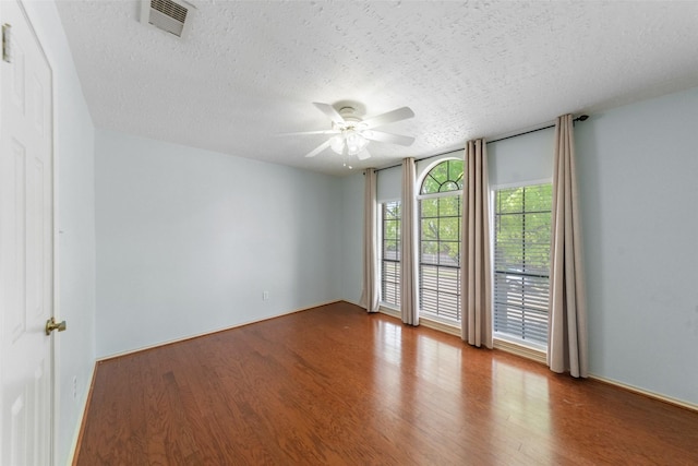 unfurnished room with wood finished floors, a textured ceiling, a ceiling fan, and visible vents