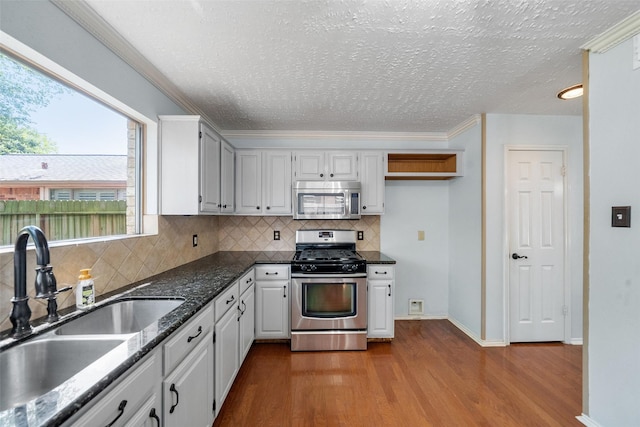 kitchen featuring dark wood-style floors, backsplash, a sink, a textured ceiling, and appliances with stainless steel finishes