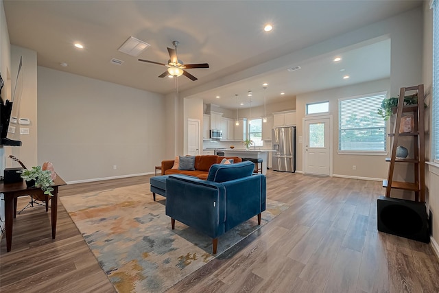 living area featuring light wood finished floors, ceiling fan, baseboards, and recessed lighting