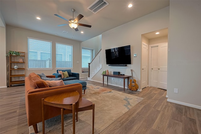living room with stairs, visible vents, baseboards, and ceiling fan