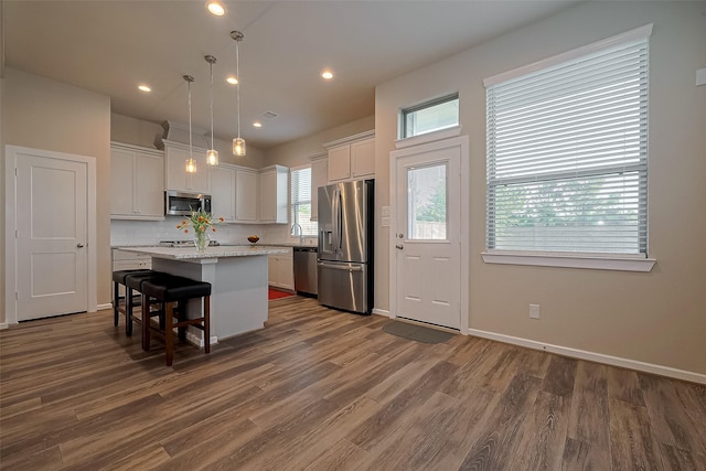 kitchen with backsplash, a kitchen island, white cabinets, dark wood-type flooring, and stainless steel appliances