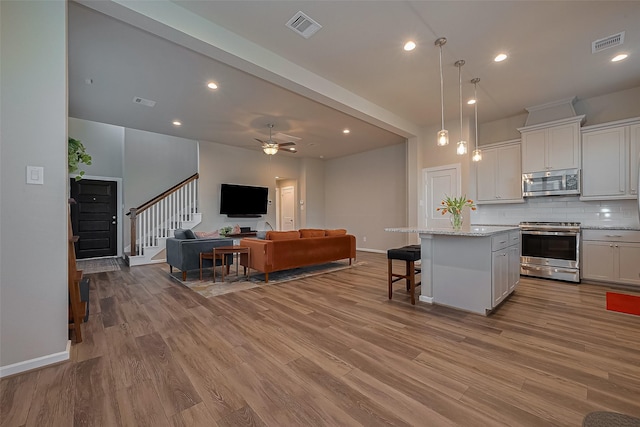 kitchen with a kitchen island, open floor plan, visible vents, and appliances with stainless steel finishes
