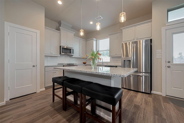 kitchen with tasteful backsplash, visible vents, a center island, appliances with stainless steel finishes, and dark wood-type flooring
