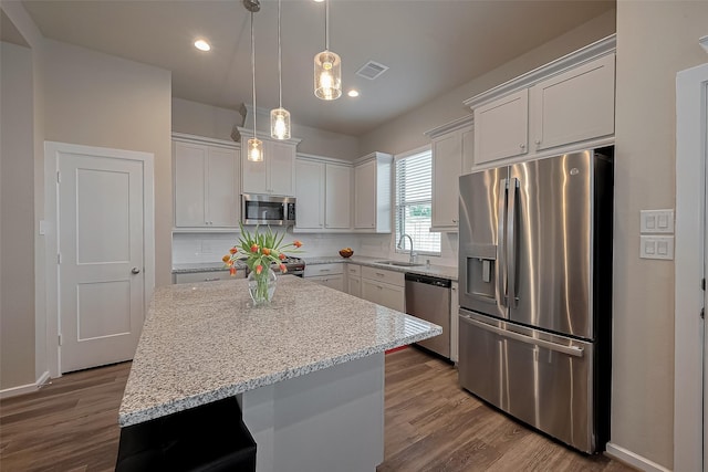 kitchen featuring tasteful backsplash, a sink, dark wood-style flooring, stainless steel appliances, and a kitchen island