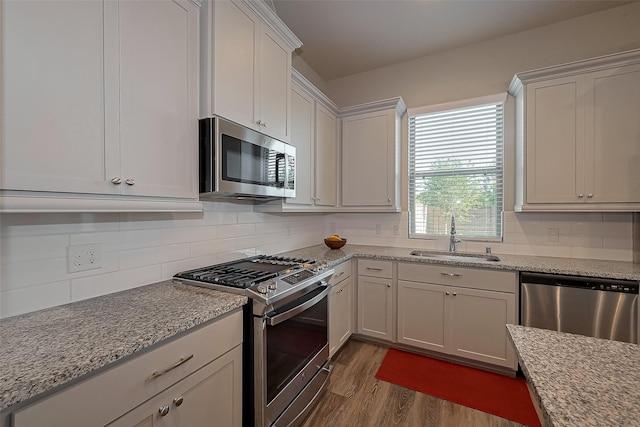 kitchen with stainless steel appliances, tasteful backsplash, dark wood-type flooring, and a sink