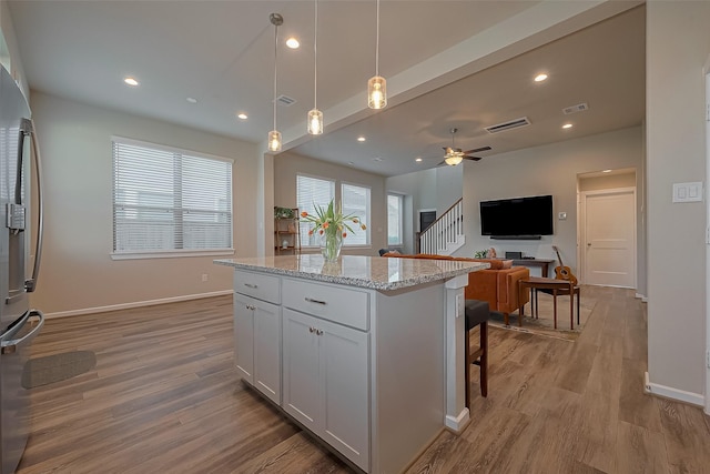 kitchen featuring light wood-style floors, stainless steel fridge with ice dispenser, visible vents, a kitchen island, and open floor plan