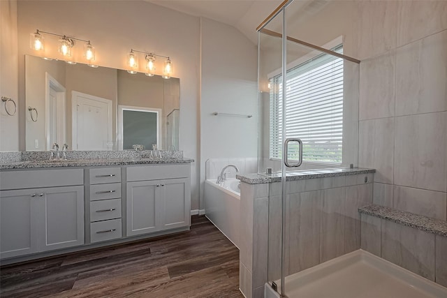 bathroom with a shower stall, a garden tub, double vanity, and wood finished floors